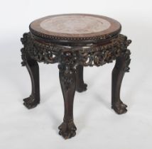 A Chinese carved darkwood stand, Qing Dynasty, the round top inset with marble, over carved and