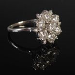A white metal diamond cluster ring, centred with a round brilliant cut diamond calculated to weigh