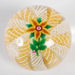 A Paul Ysart paperweight, centred with a five petal yellow flower on a radiating latticino ground,
