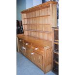 A modern pine dresser, with a three shelved plate rack on top of a base with three short drawers