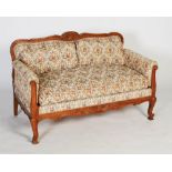 A 20th century oak upholstered two-seat sofa, the frame carved with C-scroll and floral details,