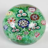 A Paul Ysart paperweight, decorated with colourful millefiori canes on a green scrambled latticino