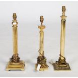 Three brass column table lamps, each with fluted columns one with a Corinthian capital, the
