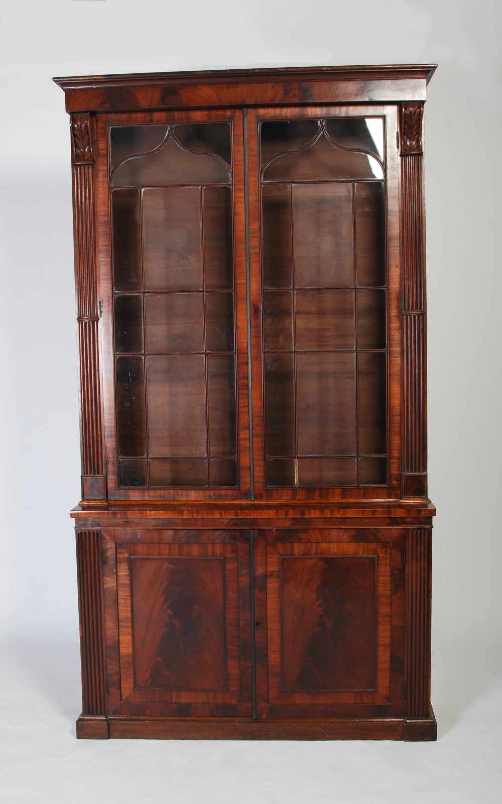 A 19th century mahogany bookcase of slender proportion, the large glazed doors flanked by two reeded