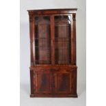 A 19th century mahogany bookcase of slender proportion, the large glazed doors flanked by two reeded