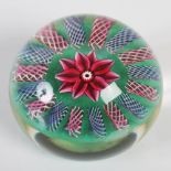 A Paul Ysart 3D paperweight, centred with a ten petal pink flower on a green ground within a
