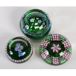 Three Perthshire Paperweights, comprising; a pink and white five petal flower weight on a green