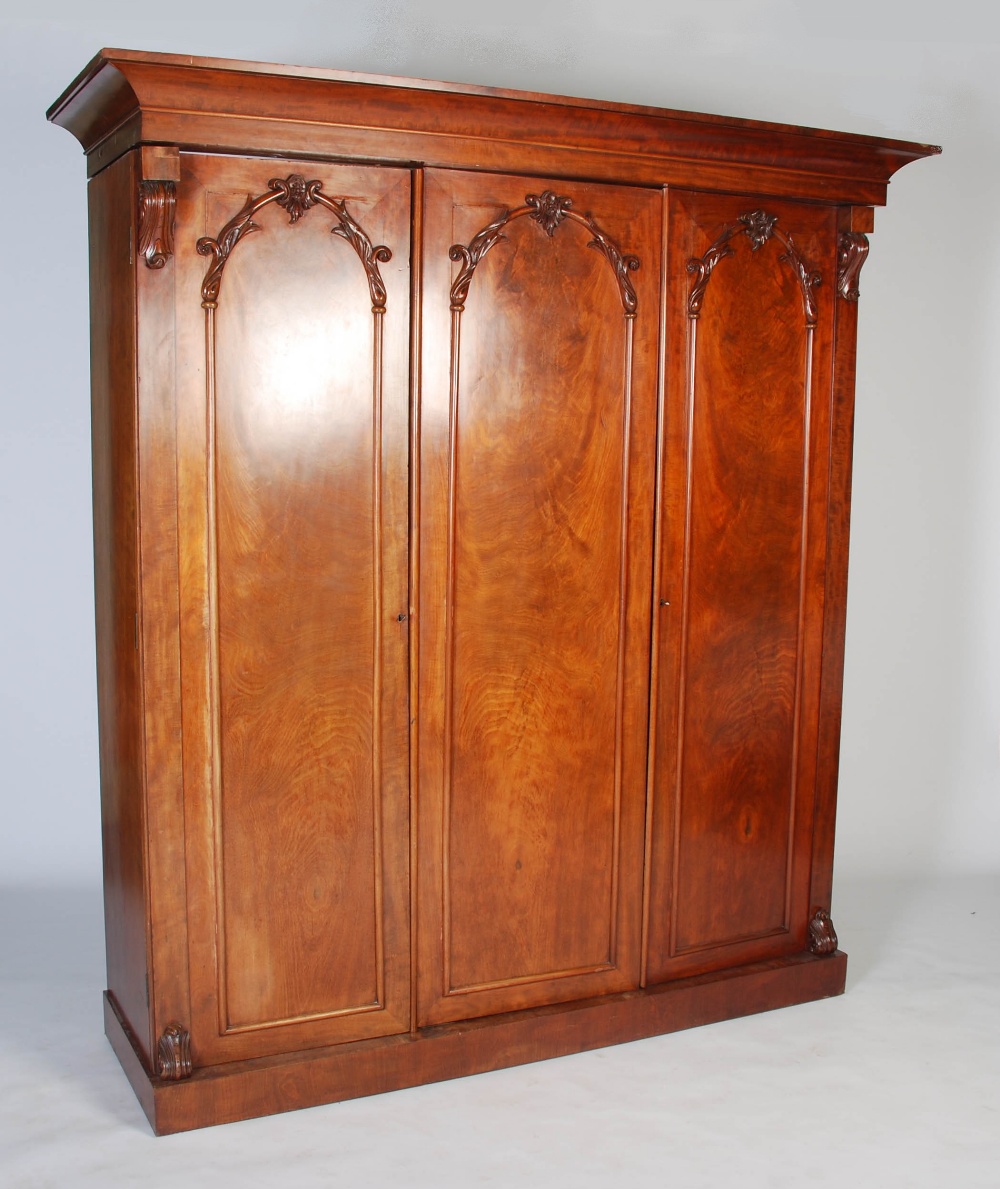 A late 19th century mahogany triple section wardrobe, with a rectangular cavetto pediment atop three