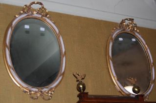 A pair of 20th century gilt gesso oval mirrors, the frames with inner gilt beaded rim and white