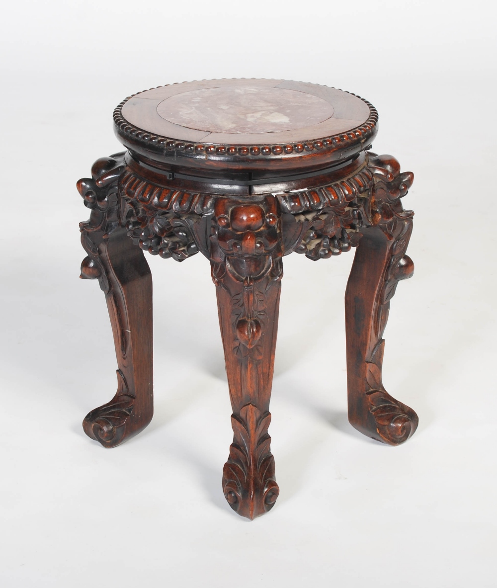 A Chinese carved darkwood stand, Qing Dynasty, the round top inset with marble, over carved and