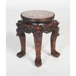 A Chinese carved darkwood stand, Qing Dynasty, the round top inset with marble, over carved and