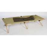 A folding military style camp bed, the wooden and metal frame with green canvas stretcher, inside
