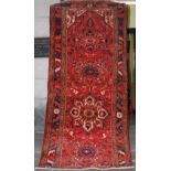 A Persian Heriz rug, the red field with floral motifs around four lobbed cream and indigo floral