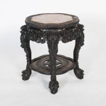 A Chinese carved darkwood stand, Qing Dynasty, the round top carved with a frieze of auspicious