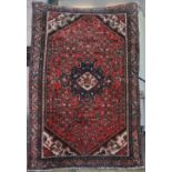 A Persian Heriz rug, the red field with interwoven medallions and floral motifs around a indigo
