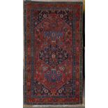 A Persian Heriz rug, the red field with floral motifs around large indigo medallion, with indigo