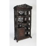 A Chinese carved darkwood display cabinet, Qing Dynasty, the arched top above a staggered