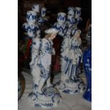 Pair of Dresden style blue and white two-branch candlesticks, including a figure of a gentleman in