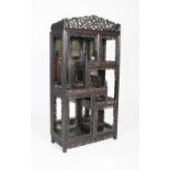 A Chinese carved darkwood display cabinet, Qing Dynasty, the arched top above a staggered