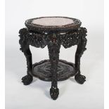 A Chinese carved darkwood stand, Qing Dynasty, the shaped round top carved with a frieze of