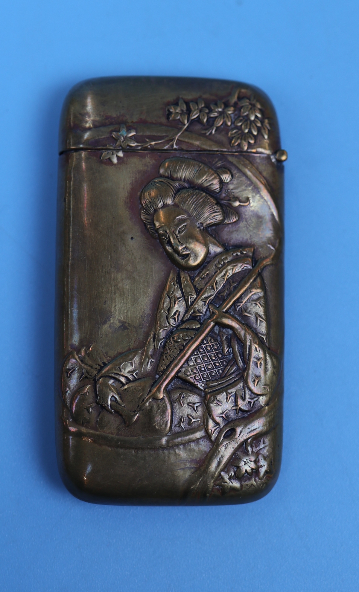 A brass novelty vesta case embossed with the figure of a Japanese Geisha and bamboo on the other