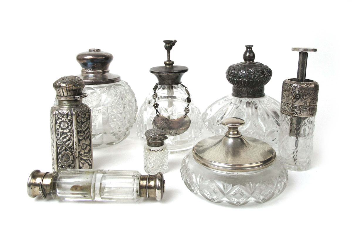 A collection of silver and white metal topped cut glass scent bottles and pots to include a double