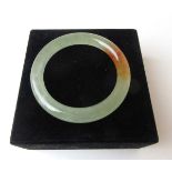 A pale green and brown jade bangle, internal diameter approx. 5.