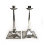 A pair of Edwardian Arts and Crafts silver candlesticks,
