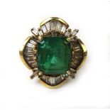 An 18ct gold, emerald and diamond cluster ring of stylized form. The approximately 6.