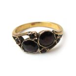 An early Victorian yellow metal and garnet ring, the stones in a stylized crossover setting.