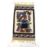 A handwoven South American rug, the border surrounding a warrior in headdress,