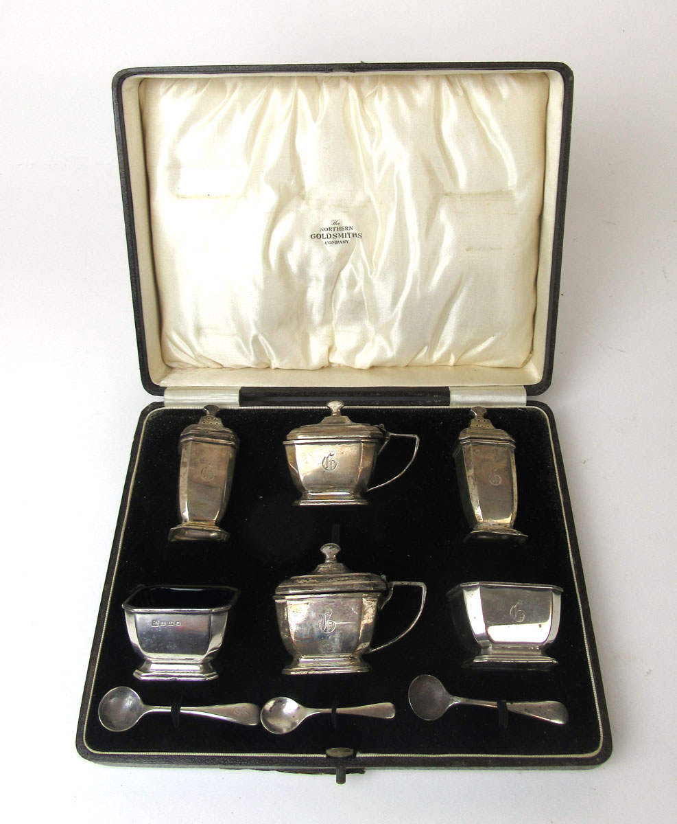 A George V silver cruet set comprising of two mustard pots,