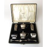 A George V silver cruet set comprising of two mustard pots,