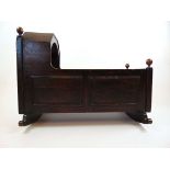 An 18th century oak and pine crib, the canopy and finial's over the faux panel sides on rocker base,