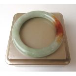 A pale green and brown jade bangle, internal diameter approx. 5.