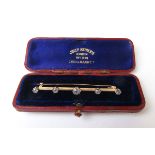 An early 20th century yellow metal bar brooch set with five old cut diamonds.