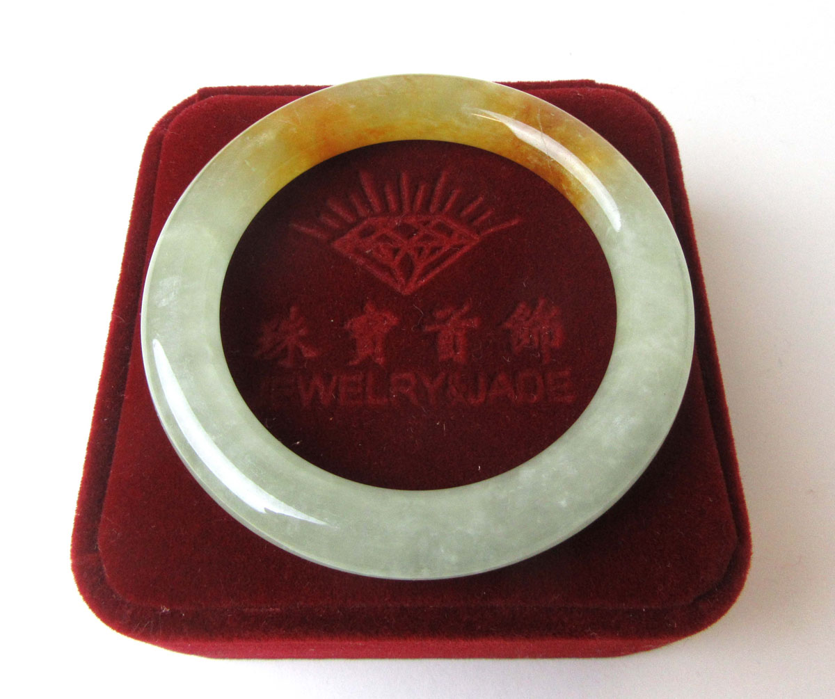A pale green and brown jade bangle, internal diameter approx. 5.