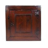 A mid 18th century oak wall hanging cabinet, the single panel door revealing fixed shelving, h.