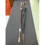 A cane walking stick with a white metal top together with a black parasol