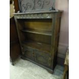 A mid 20th century stained oak bookcase having open storage above two cupboard doors