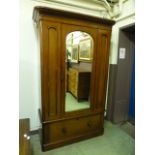 A Victorian mahogany veneered wardrobe having a mirrored bevelled glass centre door with drawer to