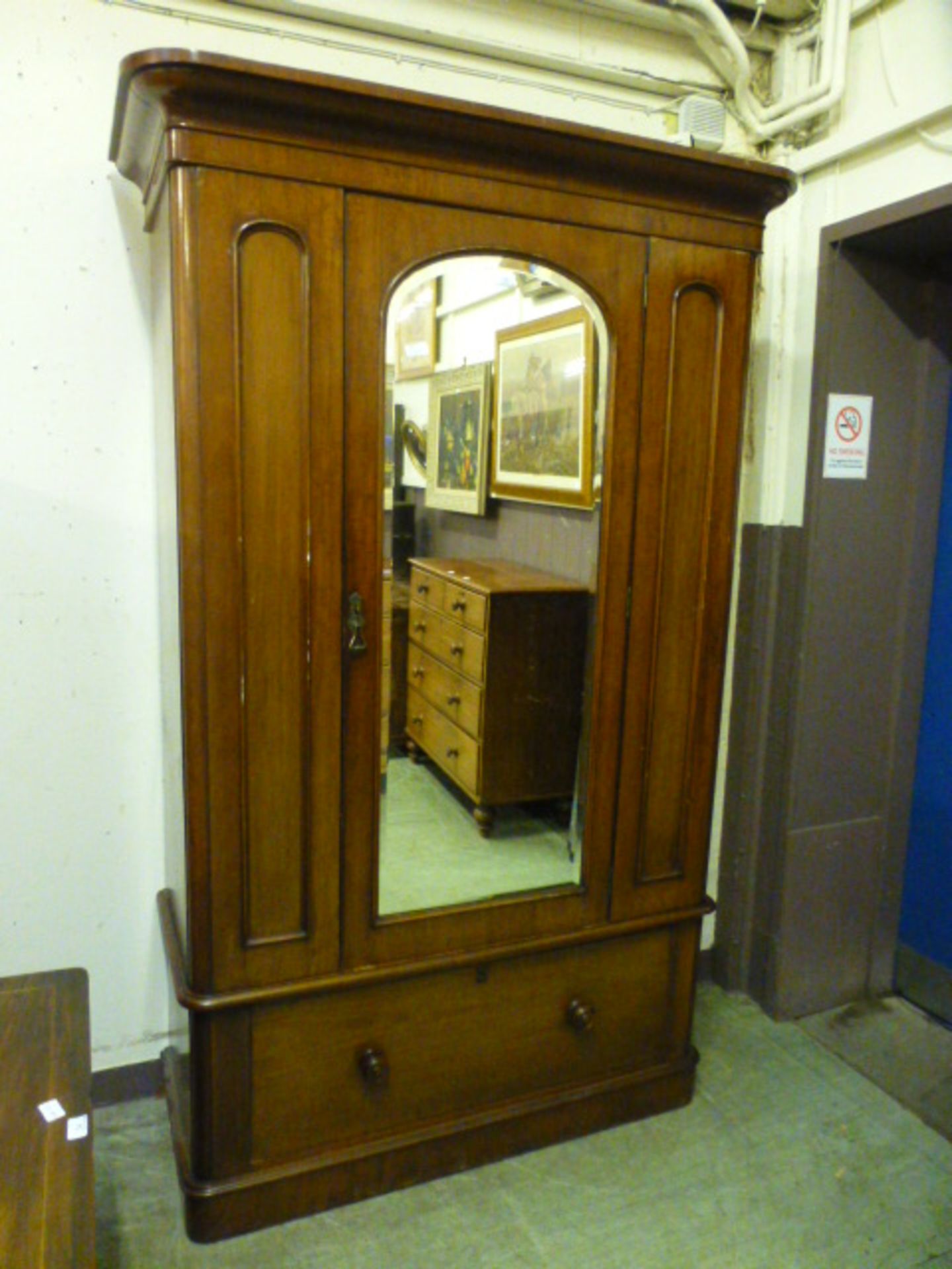 A Victorian mahogany veneered wardrobe having a mirrored bevelled glass centre door with drawer to