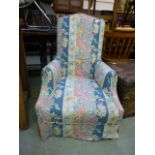 An Edwardian walnut framed nursing chair upholstered in a loose floral fabric