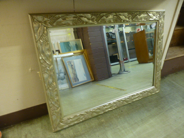 A silvered floral framed beveled glass rectangular mirror