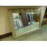 A silvered floral framed beveled glass rectangular mirror