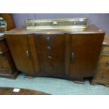 A 1950s oak veneered sideboard having four drawers flanked by cupboard doors