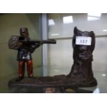 An early 20th century novelty cast metal money box in the form of a soldier shooting a tree trunk