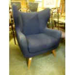 A modern high back wing armchair upholstered in a blue fabric