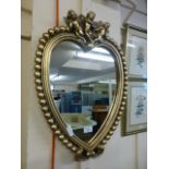 A gilt framed heart shaped mirror with cherubs to top