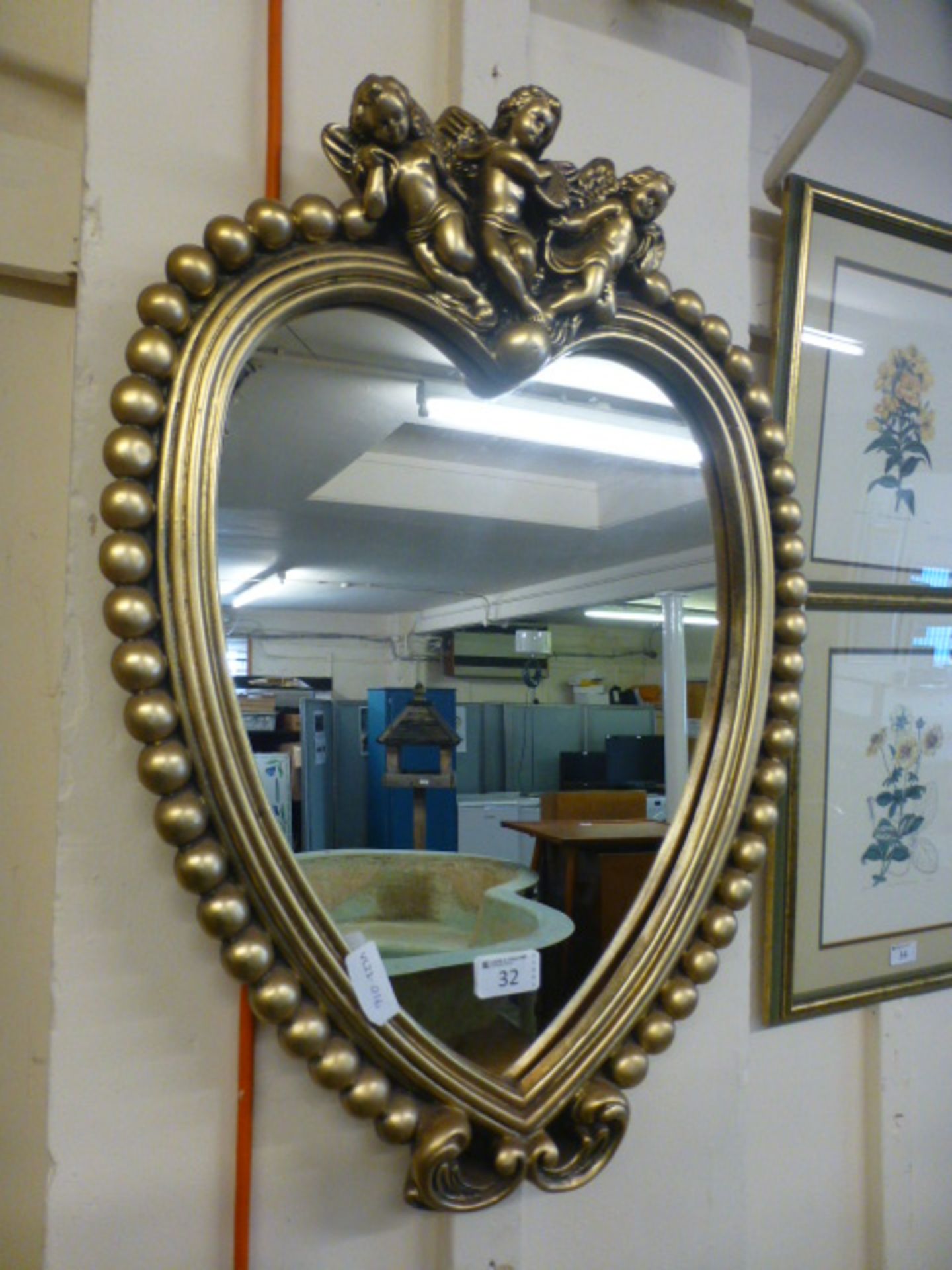 A gilt framed heart shaped mirror with cherubs to top